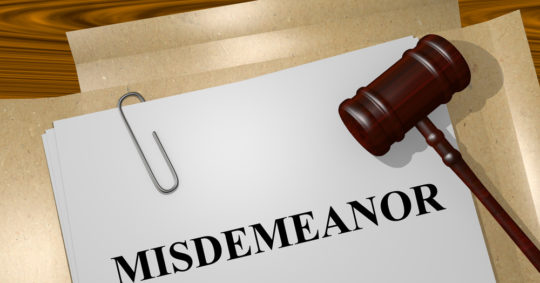 “Misdemeanor” written on documents in a folder next to gavel
