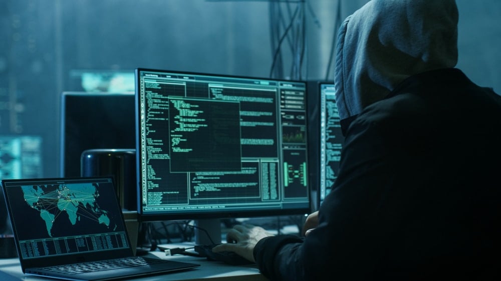 hooded hacker working on computers