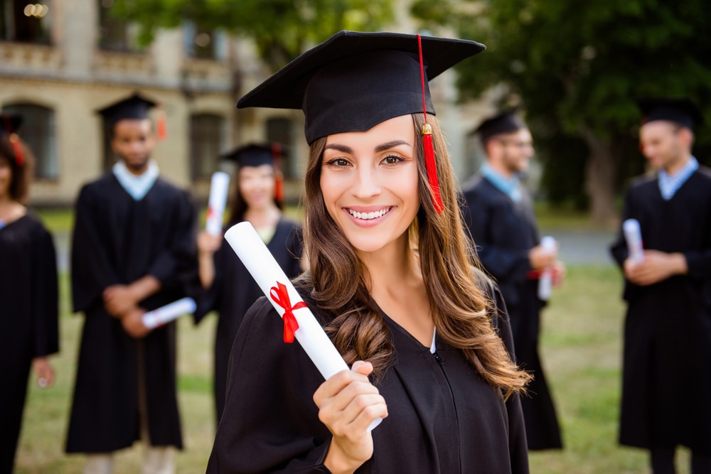student smiling with diploma in hand
